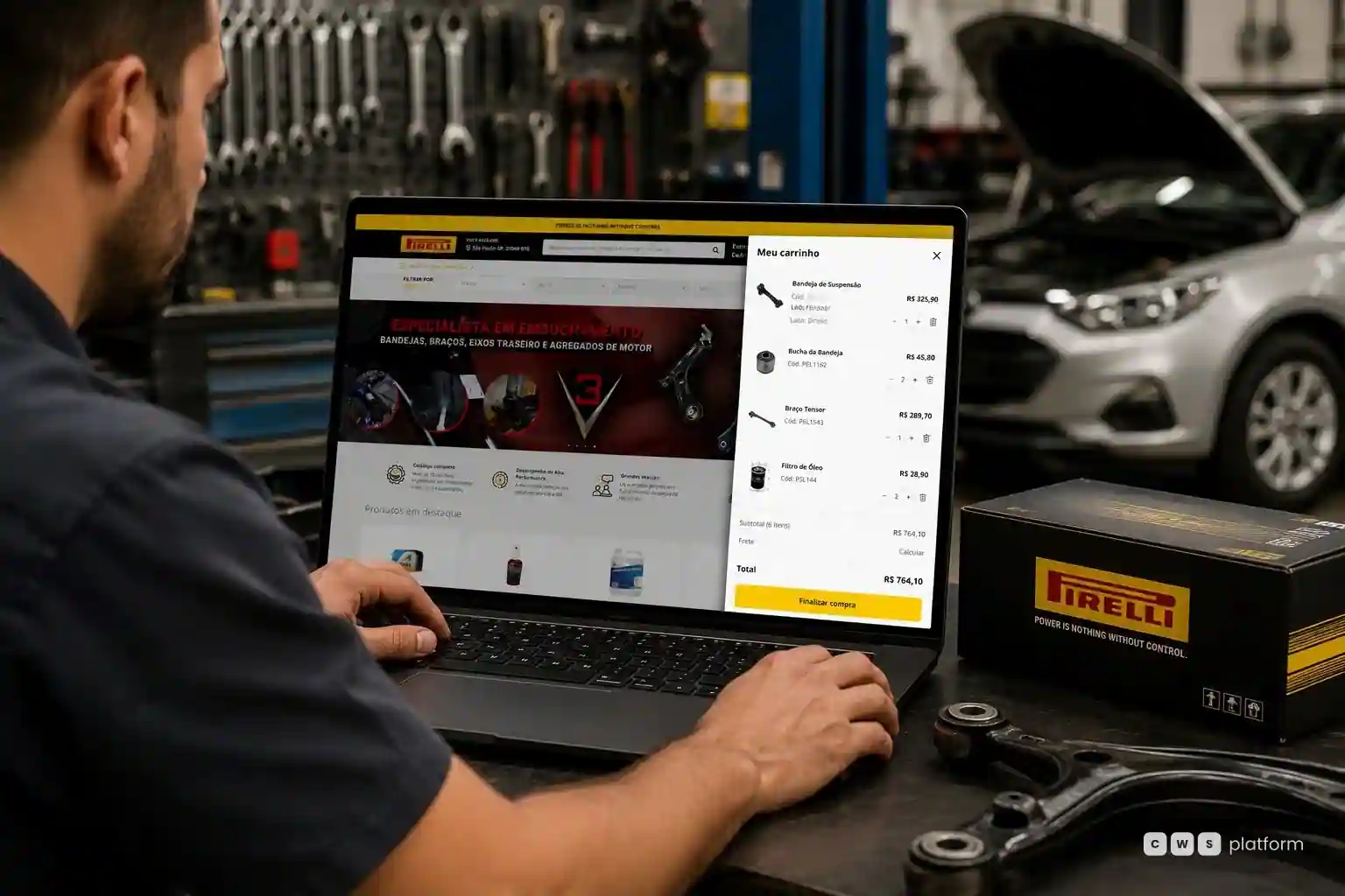 Mecânico em oficina acessa portal Pirelli no notebook com carrinho de peças aberto